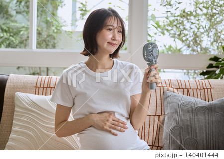 ハンディファンで涼む妊婦の女性 ハンディファンで涼む妊婦の女性 140401444