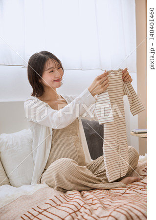 ベビー服を手に取り笑顔で眺める妊婦の女性 140401460
