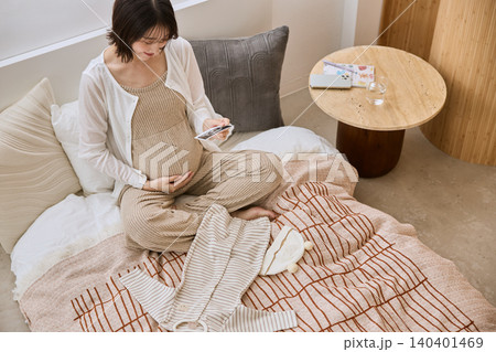 エコー写真を見ながらお腹に手を当てる妊婦 140401469