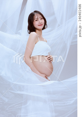 白い布に包まれた妊婦の女性 穏やかなマタニティのイメージ 白い布に包まれた妊婦の女性 穏やかなマタニティのイメージ 140401486