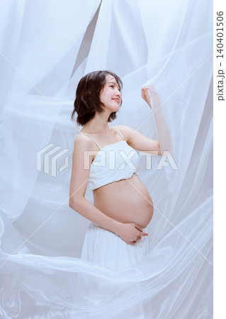 白い布に包まれた妊婦の女性 穏やかなマタニティのイメージ 白い布に包まれた妊婦の女性 穏やかなマタニティのイメージ 140401506