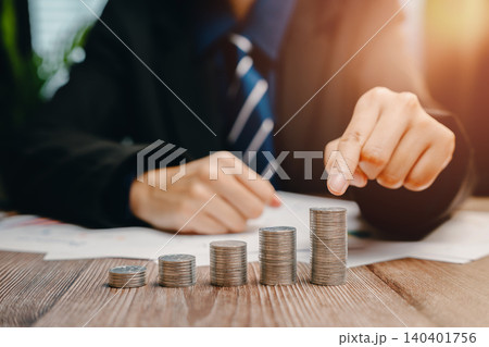 Businessman Analyzing Financial Growth with Coins on Table in Modern Office Environment, Business concept 140401756