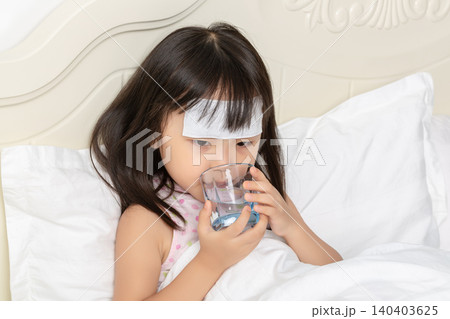 Sick Asian Little Girl Drinking Water in Bed with Fever Patch Sick Asian Little Girl Drinking Water in Bed with Fever Patch 140403625