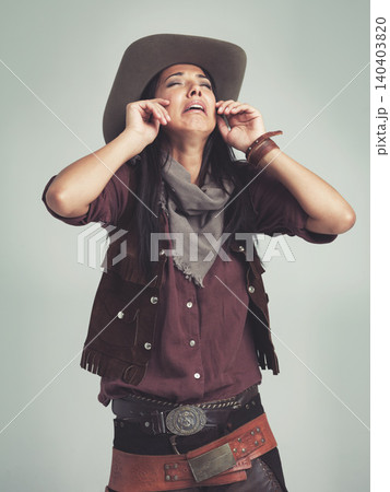 Crying, cowgirl and unhappy with sad expression in studio with stress, tears and upset with sorrow. Female person, costume and hat for western fashion, isolated and emotional with grey background Crying, cowgirl and unhappy with sad expression in studio with stress, tears and upset with sorrow. Female person, costume and hat for western fashion, isolated and emotional with grey background 140403820