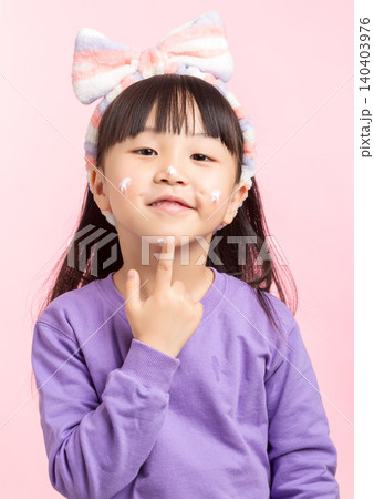 A studio photo of an Asian girl applying face cream after washing her face. 140403976