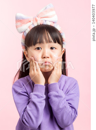 A studio photo of an Asian girl applying face cream after washing her face. 140403977
