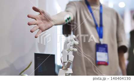Man controlling a robotic hand with EMG sensors on his arm in a tech lab Man controlling a robotic hand with EMG sensors on his arm in a tech lab 140404130