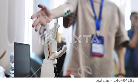 A person controls an artificial robotic arm via wires on their hand. A person controls an artificial robotic arm via wires on their hand. 140404185