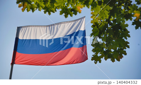 Russian flag waving with green maple leaves against a clear blue sky Russian flag waving with green maple leaves against a clear blue sky 140404332