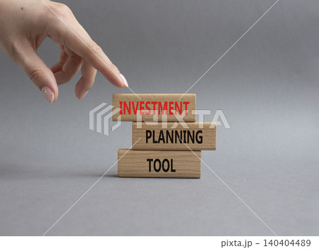 Investment planning tool symbol. Concept word Investment planning tool on wooden blocks. Businessman hand. Beautiful grey background. Business and Investment planning tool. Copy space Investment planning tool symbol. Concept word Investment planning tool on wooden blocks. Businessman hand. Beautiful grey background. Business and Investment planning tool. Copy space 140404489