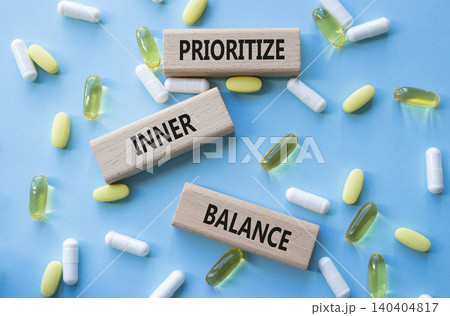 Prioritize inner balance symbol. Concept words Prioritize inner balance on wooden blocks. Beautiful blue background with pills. Healthcare and Prioritize inner balance concept. Copy space. 140404817