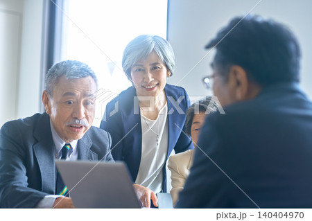 会議室でカメラに向かって立つシニアのビジネスグループ 140404970