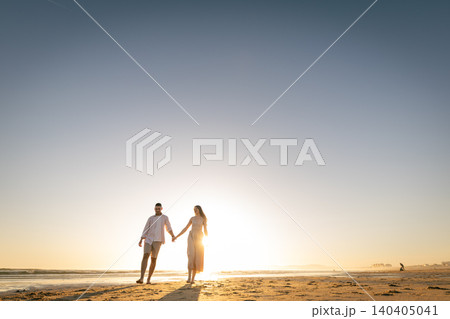 Couple walking hand in hand on the beach during sunset close to the horizon 140405041