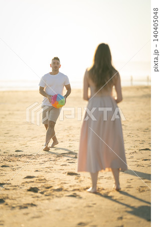 People playing with a colorful beach ball on the sand during a sunny day near the shore People playing with a colorful beach ball on the sand during a sunny day near the shore 140405048