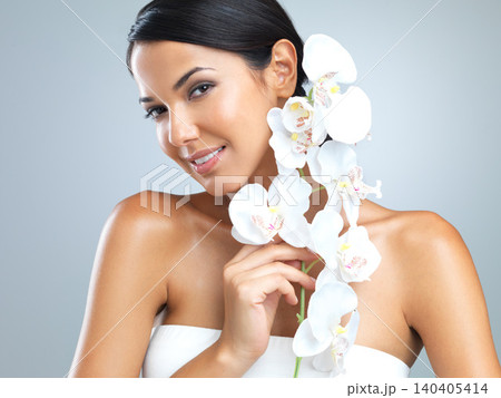 Portrait, woman and beauty with flower in smile on studio, grey background and satisfied with makeup. Female person, soft and natural for smooth skin with eco friendly, sustainable and happiness. 140405414