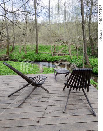 Wooden terrace with lounge chairs by a forest stream. Wooden terrace with lounge chairs by a forest stream. 140405502