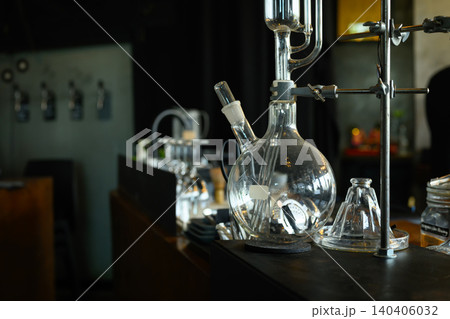 Glass Laboratory Flask and Distillation Apparatus on Dark Workbench in Scientific Setting Glass Laboratory Flask and Distillation Apparatus on Dark Workbench in Scientific Setting 140406032