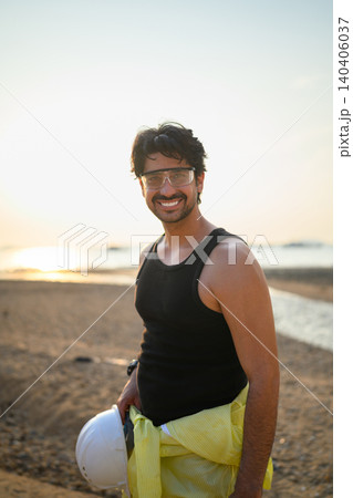 Smiling industrial engineer standing at coastal energy site during sunset Smiling industrial engineer standing at coastal energy site during sunset 140406037