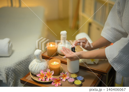 Cropped shot woman hand preparing spa tools with candles herbal compress and warm relaxing atmosphere 140406067