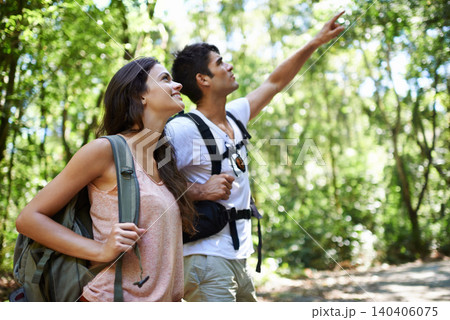 Happy couple, backpack and pointing with direction for sightseeing, destination or hiking together in nature. Young man and woman with smile, bag and showing path or route for trekking in forest 140406075