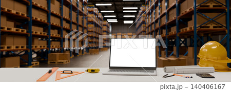 Engineering workspace empty screen laptop computer with safety equipment and drafting tools inside modern warehouse 140406167