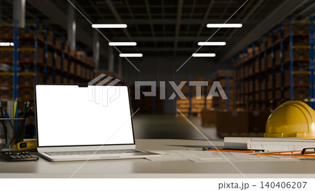 Engineering workspace empty screen laptop computer with safety equipment and drafting tools inside modern warehouse Engineering workspace empty screen laptop computer with safety equipment and drafting tools inside modern warehouse 140406207