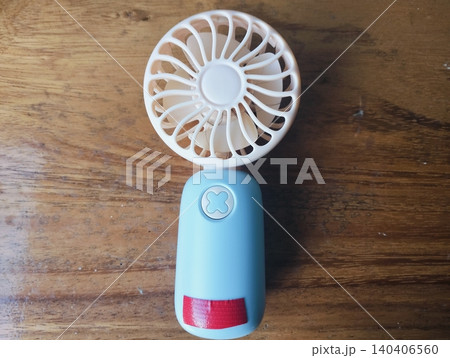 Compact Mini Electric Fan for Personal Cooling on a wooden table Compact Mini Electric Fan for Personal Cooling on a wooden table 140406560