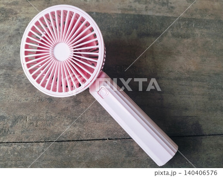 Compact Mini Electric Fan for Personal Cooling on a wooden table Compact Mini Electric Fan for Personal Cooling on a wooden table 140406576