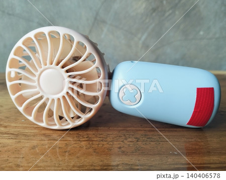 Compact Mini Electric Fan for Personal Cooling on a wooden table Compact Mini Electric Fan for Personal Cooling on a wooden table 140406578