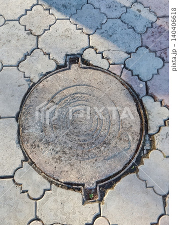 Concrete manhole cover on patterned pavement in urban setting with weathered texture Concrete manhole cover on patterned pavement in urban setting with weathered texture 140406618