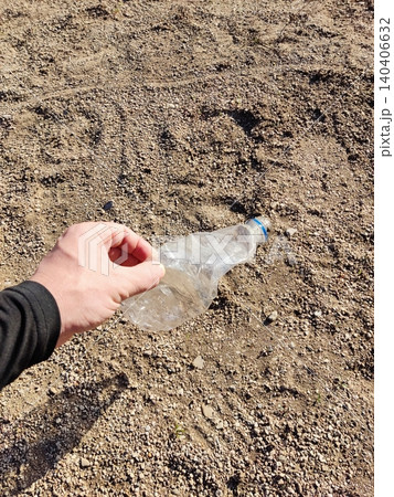 Cleaning effort: hand holding plastic bottle on gravel to promote environmental awareness Cleaning effort: hand holding plastic bottle on gravel to promote environmental awareness 140406632