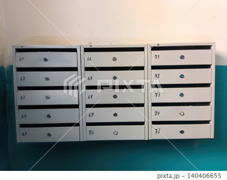 Organized row of white metal mailboxes with numbers on teal wall Organized row of white metal mailboxes with numbers on teal wall 140406655