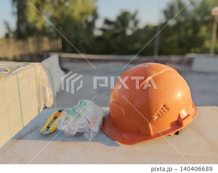 Orange safety helmet and work gloves on outdoor construction site 140406689