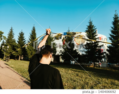 Person practicing ribbon dancing outdoors near colorful building and trees 140406692