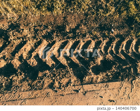 Tire tracks on muddy ground creating rugged texture in natural setting 140406700