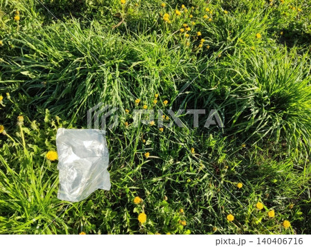 Plastic bag in lush green grass with yellow dandelions Plastic bag in lush green grass with yellow dandelions 140406716