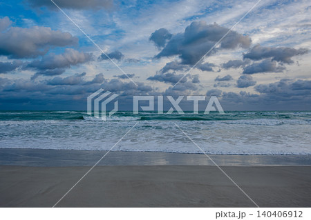 Waves crash on the shore under a cloudy sky at twilight on a beach Waves crash on the shore under a cloudy sky at twilight on a beach 140406912