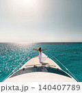Young woman in white dress standing on yacht bow over turquoise sea 140407789
