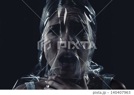 Scary, face and woman with plastic or bag in horror, drama or death in dark background of studio. Suffocating, murder and girl with fear from crime, victim and trapped in trash, garbage or pollution Scary, face and woman with plastic or bag in horror, drama or death in dark background of studio. Suffocating, murder and girl with fear from crime, victim and trapped in trash, garbage or pollution 140407963