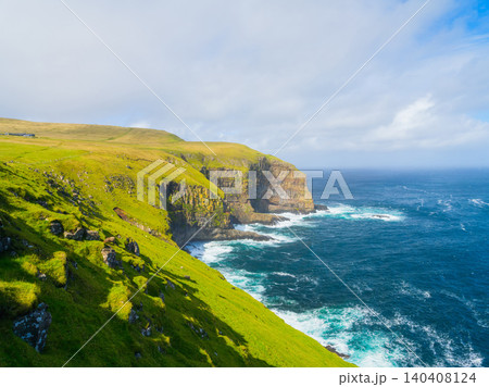 Scenic summer landscape of Faroe Islands with green fields, meadows and rocky cliffs by the ocean. Scenic summer landscape of Faroe Islands with green fields, meadows and rocky cliffs by the ocean. 140408124
