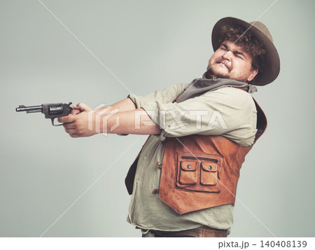 Cowboy, funny man and shooting gun in studio, weapon and pistol for western fight isolated on a white background. Plus size, criminal and person with revolver, scared or guess aim with fear in Texas Cowboy, funny man and shooting gun in studio, weapon and pistol for western fight isolated on a white background. Plus size, criminal and person with revolver, scared or guess aim with fear in Texas 140408139