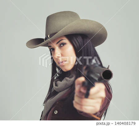 Woman, cowgirl and portrait or pointing weapon for wild west costume on white background, rodeo or outfit. Female person, revolver and cowboy hat in studio for Texas dress up, confidence or mockup Woman, cowgirl and portrait or pointing weapon for wild west costume on white background, rodeo or outfit. Female person, revolver and cowboy hat in studio for Texas dress up, confidence or mockup 140408179