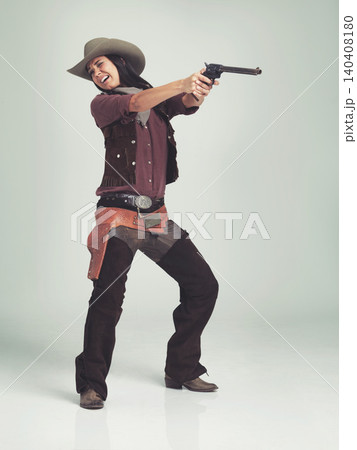Western, woman and cowboy with gun in studio for fashion, nervous and scared to shoot on grey background. Female person, vintage and outlaw with pistol for wild west, costume and character with hat 140408180