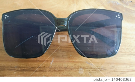 Black Oversized Sunglasses on Wooden Surface Close-Up Black Oversized Sunglasses on Wooden Surface Close-Up 140408362