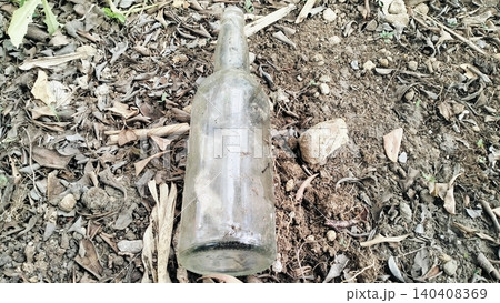 Dirty Empty Glass Bottle Discarded on Dry Ground 140408369
