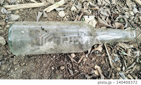 Dirty Empty Glass Bottle Discarded on Dry Ground Dirty Empty Glass Bottle Discarded on Dry Ground 140408372