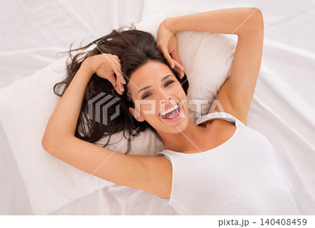 Portrait, happy and top view of woman on bed in home to relax or resting in the morning. Face, above and excited person in bedroom on comfortable pillow, wakeup or laughing in apartment in Australia 140408459