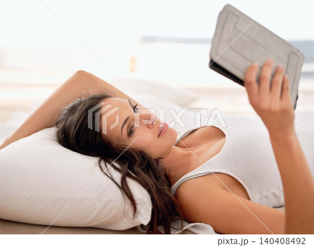 Woman, tablet and reading in bed, morning and story with ebook for knowledge, information or novel. Girl, person and happy to relax in bedroom with digital touchscreen for streaming app at apartment 140408492