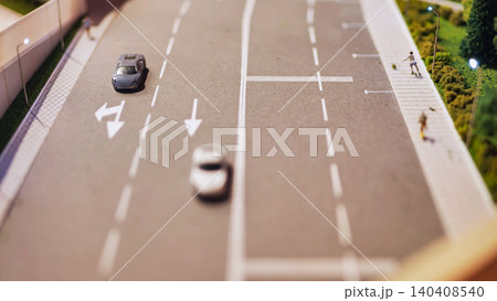 Miniature diorama showing toy cars driving on a road with streetlights and pedestrian Miniature diorama showing toy cars driving on a road with streetlights and pedestrian 140408540