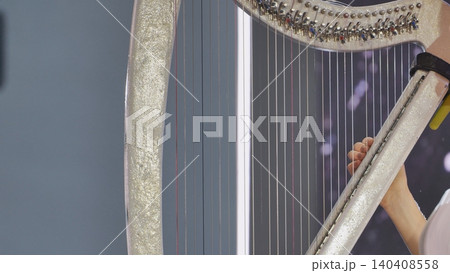 Harpist performing classical music with elegant details, playing strings during a show Harpist performing classical music with elegant details, playing strings during a show 140408558